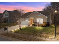 Tan house with stone accents, a white garage door, and landscaping at 3215 Osceola Ln, Charlotte, NC 28269