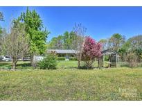 Beautiful landscaped front yard with mature trees and a charming wooden gazebo at 16415 Capps Rd, Charlotte, NC 28278