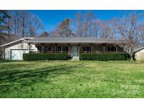 Charming ranch-style home with inviting covered porch, attached garage, and lush green lawn at 16415 Capps Rd, Charlotte, NC 28278