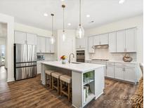 Bright, open kitchen featuring a large center island with seating and pendant lighting at 212 Portrait Way, Indian Trail, NC 28079