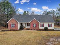 Brick ranch home with a landscaped yard and attached porch at 1055 Cedar Hills Ln, Lancaster, SC 29720