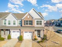 Two-story townhome with brick and siding exterior, two-car garage, and landscaping at 13417 Savannah Club Dr, Charlotte, NC 28273