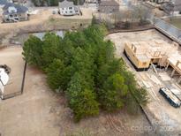 Aerial view of a home under construction surrounded by mature trees and a pond at 14108 Rhone Valley Dr, Charlotte, NC 28278