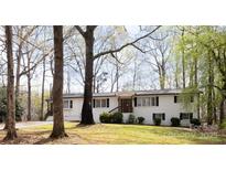 Charming white brick home with black shutters and a cozy front porch nestled among mature trees at 1035 Timberlane Dr, Lincolnton, NC 28092