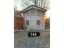 Tan mobile home with three windows and a black address marker at 145 Arrowood Trl # 61F, Mount Gilead, NC 27306