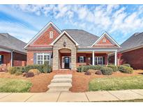 Charming brick home featuring stone accents, covered porch, landscaped front yard, and a welcoming entrance at 535 Chalmers Row, Rock Hill, SC 29732