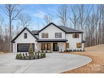 Stunning two-story home with white brick, black accents, elegant landscaping, and a circular driveway at 3415 Waxhaw Indian Trail S Rd, Waxhaw, NC 28173