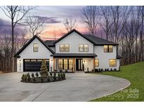 Stunning two-story home with white brick, black trim, circular driveway, and manicured landscaping at 3415 Waxhaw Indian Trail S Rd, Waxhaw, NC 28173