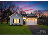 Newly built home with gray siding, white garage door, and landscaped lawn at 5517 Skycrest Dr, Charlotte, NC 28269