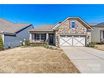 Charming single-Gathering home featuring a stone facade, manicured lawn, and a two-car garage at 7029 Overjoyed Xing, Charlotte, NC 28215