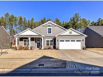 Gray house with white trim, three-car garage, and a manicured lawn at 8825 Chapel Grove Crossing Dr, Huntersville, NC 28078