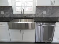 Stainless steel farmhouse sink, granite countertops, and modern dishwasher in this updated kitchen at 1408 Delview Rd, Cherryville, NC 28021