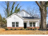 Charming white house with brick base and black front door, newly landscaped yard at 310 W 4Th Ave, Gastonia, NC 28052