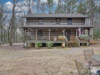 Rustic log cabin home nestled in a wooded setting, featuring a large wrap-around porch at 2577 Dutch Rd, Mount Pleasant, NC 28124