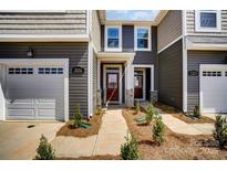 Charming townhome showcasing a covered entryway, a garage and manicured landscaping adding to the curb appeal at 7232 Hodges Meadow Ln, Charlotte, NC 28213