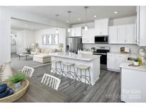 Open concept kitchen features island with seating, stainless steel appliances, and white cabinetry at 7232 Hodges Meadow Ln, Charlotte, NC 28213