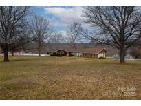 Brick ranch house with large yard, white fence, and mature trees at 2448 Moss Farm Rd, Hickory, NC 28602