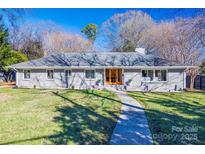 Gray brick ranch home with double wood doors, landscaped lawn, and walkway at 2861 Sharon Rd, Charlotte, NC 28211