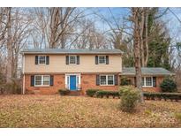 Brick two-story house with a blue door, nestled among trees at 6800 April Ln, Charlotte, NC 28215