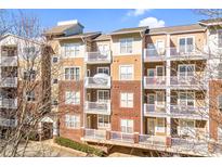 Brick building with multiple units, private balconies, and ample parking at 1000 E Woodlawn Rd # 105, Charlotte, NC 28209