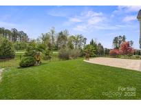 A backyard features a well-manicured lawn, mature trees and professional landscaping, as well as an outdoor patio at 253 Stone Mountain Way, Denver, NC 28037