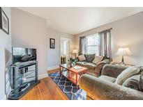 Cozy living room featuring hardwood floors, comfortable seating, and a large TV at 2516 Columbus Cir, Charlotte, NC 28208