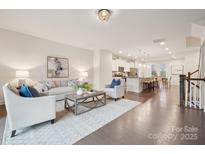 Open concept living room featuring hardwood floors, neutral paint, modern furniture, and seamless transition to the kitchen at 1252 Madison Towns Ln, Charlotte, NC 28209