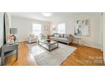 Bright living room with hardwood floors, comfy seating, and large windows at 1300 Rama Rd, Charlotte, NC 28211