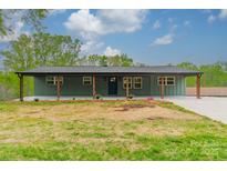 Charming one-story brick home featuring large front porch with wooden pillars and beautifully landscaped yard at 1410 Mays Chapel Church Rd, Newton, NC 28658