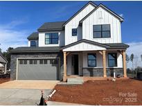 New construction home boasts a modern farmhouse design with a gray stone base, white siding, and a two-car garage at 15004 Brownleigh Ln, Huntersville, NC 28078