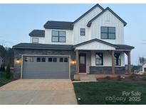Charming two-story home featuring white siding, a stone facade, and an attached two-car garage at 15004 Brownleigh Ln, Huntersville, NC 28078