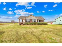 Charming brick home with a covered porch, surrounded by a spacious front yard and blue skies at 1212 Coddle Creek Hwy # 35, Mooresville, NC 28115