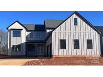 Modern farmhouse style home with board and batten siding, black trim, and a covered front porch at 13944 Roosevelt Grove Dr, Huntersville, NC 28078