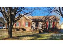 Brick ranch home with red shutters, steps up to the front door, and a yard at 1511 Sansberry Rd, Charlotte, NC 28262