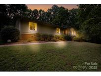 Ranch home with mature landscaping, brick walkway, and inviting nighttime ambiance at 825 W Ketchie St, China Grove, NC 28023