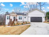 Charming white home featuring a two-car garage, wooden porch, and a well-manicured lawn at 118 Stockbridge Ln, Statesville, NC 28677