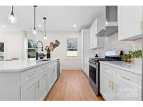 Bright kitchen features an island, stainless appliances, white cabinets, and gold hardware at 1408 Camp Greene St, Charlotte, NC 28208