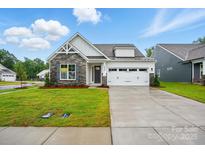 Charming home with stone accents, white siding, a well-manicured lawn, and a two-car garage at 4003 Grace Pointe Dr # 99, Wesley Chapel, NC 28079
