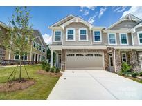 Tan two-story townhome with stone accents and a two-car garage at 14930 Tamarack Dr, Charlotte, NC 28278