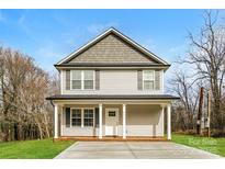 Two-story house with gray siding, a front porch, and a driveway at 571 Westside Cir, China Grove, NC 28023