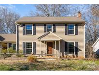 Two-story house with beige siding, black shutters, and a brown front door at 6601 Porterfield Rd, Charlotte, NC 28226