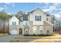 Beautiful two-story home with stone accents, a manicured lawn, and an attached two-car garage at 815 Yucatan Dr, Waxhaw, NC 28173