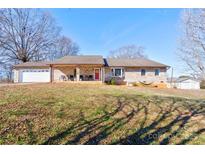 Charming ranch-style home with brick exterior, a two-car garage, a front porch, and mature trees at 1304 Cambridge Dr, Shelby, NC 28152