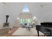 Bright living room featuring a vaulted ceiling, wood floors, and a charming wood-burning stove at 10200 Amsterdam Dr, Mount Pleasant, NC 28124