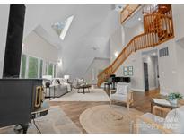 Bright living room boasts vaulted ceilings, wood floors, and a wood-burning fireplace at 10200 Amsterdam Dr, Mount Pleasant, NC 28124