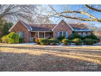 Brick ranch house with covered porch, landscaping, and a partially snow-covered yard at 110 Robin Rd, Lincolnton, NC 28092