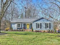 Charming ranch home with blue siding, yellow door, and landscaped lawn at 1147 Bloom Wood Ln, Matthews, NC 28105