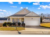 Tan house with a white garage door and landscaping at 124 Zolder Ln # 15, Mooresville, NC 28117