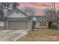 Brick ranch home with gray garage door and landscaped lawn at 14023 Kedleston Rd, Huntersville, NC 28078