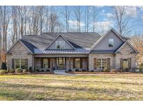 Brick home with gray metal roof, shutters, and a covered porch at 200 Barra Dr, Waxhaw, NC 28173